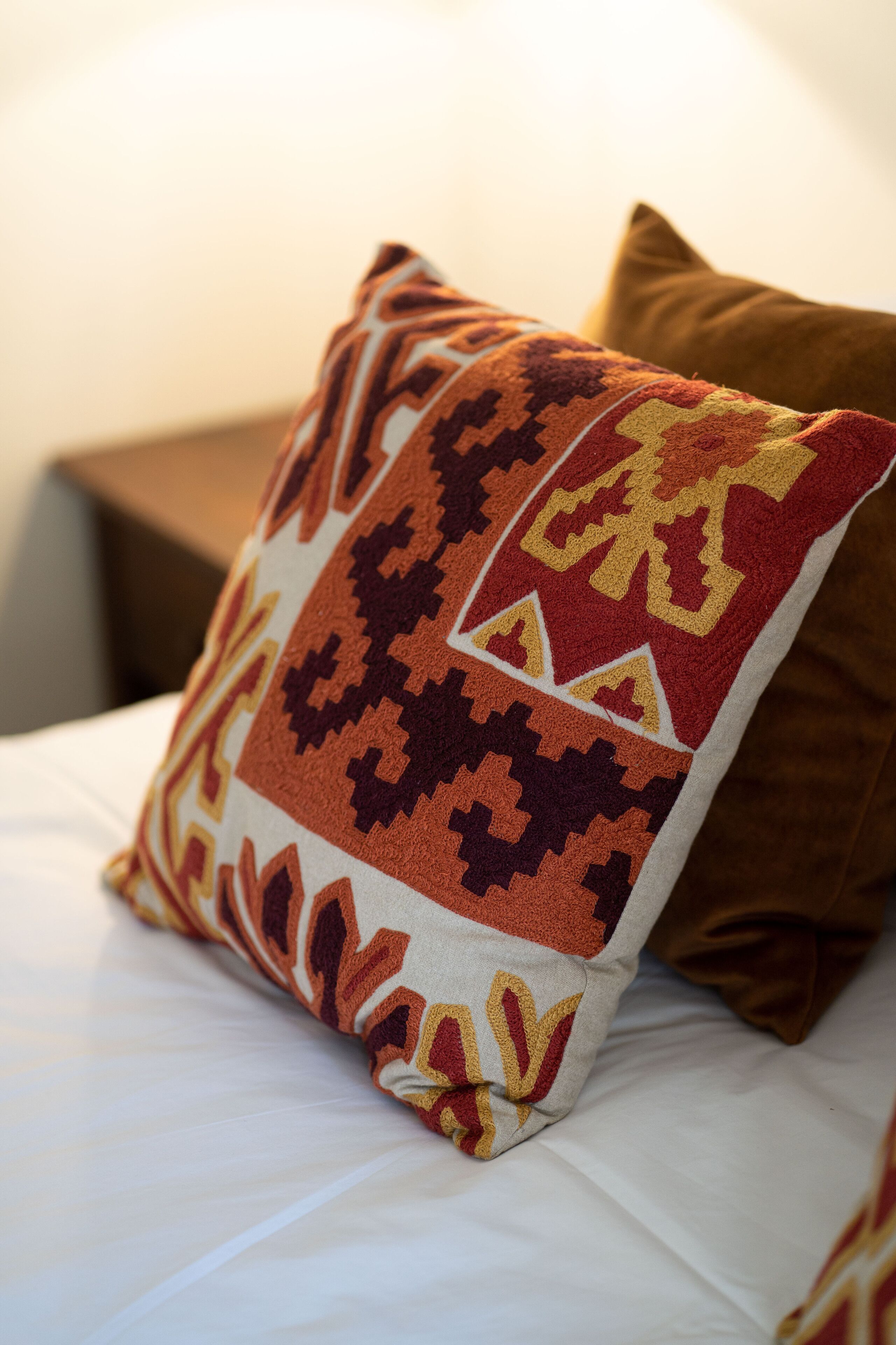 A bed with a patterned pillow and a plain pillow.