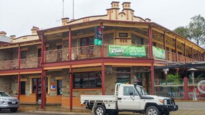 Un bâtiment à deux étages doté d’un balcon, d’une enseigne publicitaire pour des vins de la région et d’un camion garé devant.