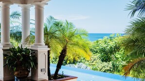 A pool area with a view of the ocean, surrounded by palm trees and columns. - Luxury Oceanfront View Villa with Chef, Housekeeping and Concierge Services (Puerto Carrillo)