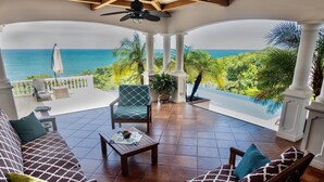 A covered patio with a view of the ocean, furnished with a sofa, chairs, and a table. - Luxury Oceanfront View Villa with Chef, Housekeeping and Concierge Services (Puerto Carrillo)