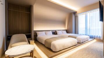 A modern hotel room with a large bed, a seating area with a table, and a TV mounted on the wall.