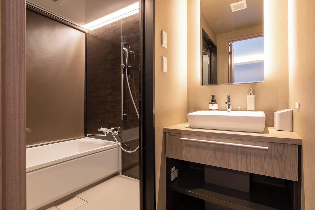 A modern bathroom with a glass-enclosed shower, a white sink, and a mirror above the vanity.