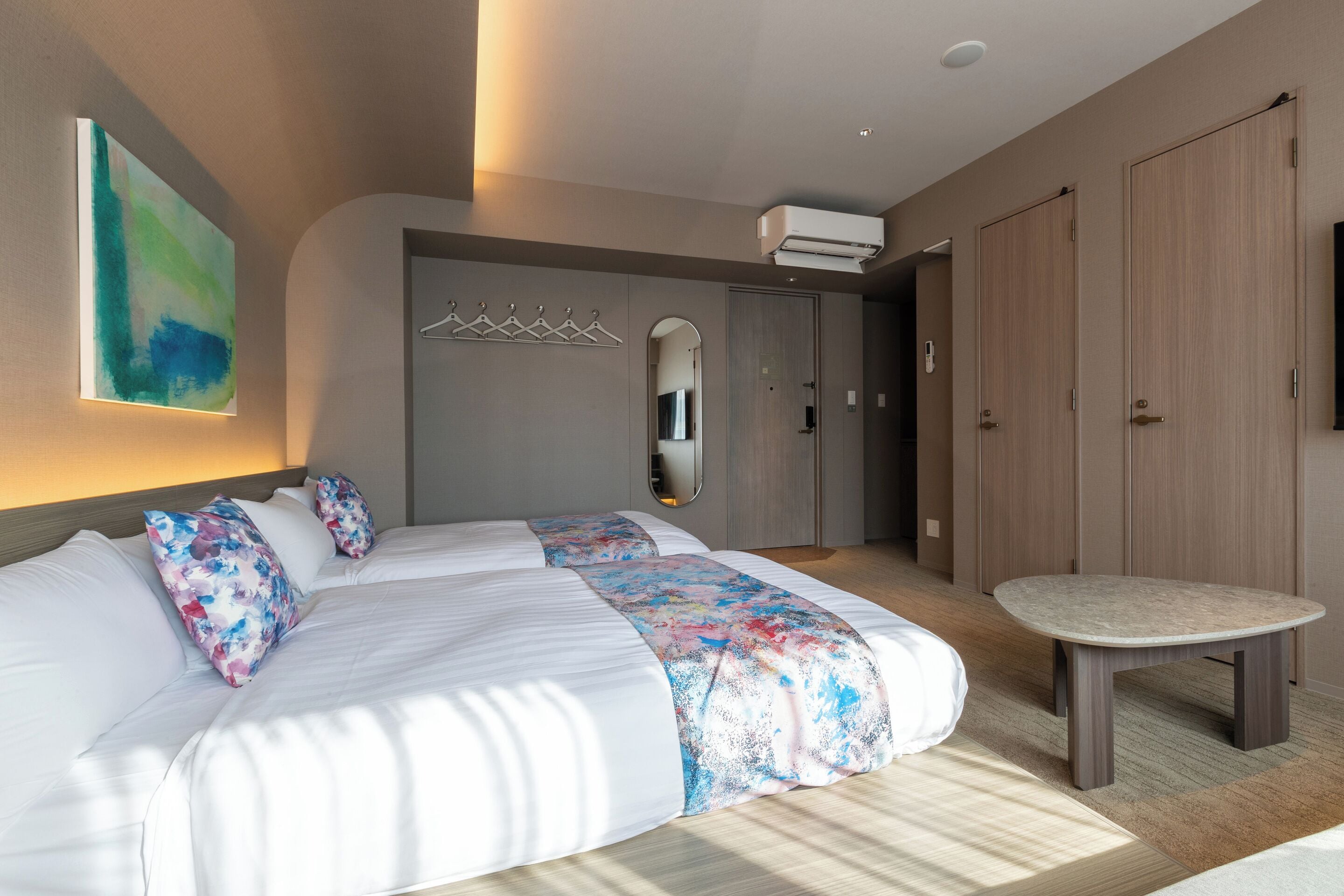 Una habitación de hotel moderna con una cama grande, una mesita redonda y un armario.