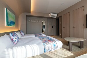 Una habitación de hotel moderna con una cama grande, una mesita redonda y un armario.