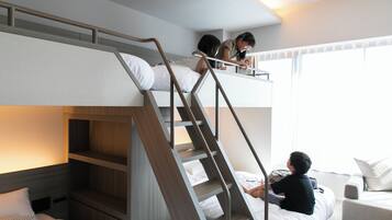 Una habitación de hotel con literas, un escritorio y un sofá.