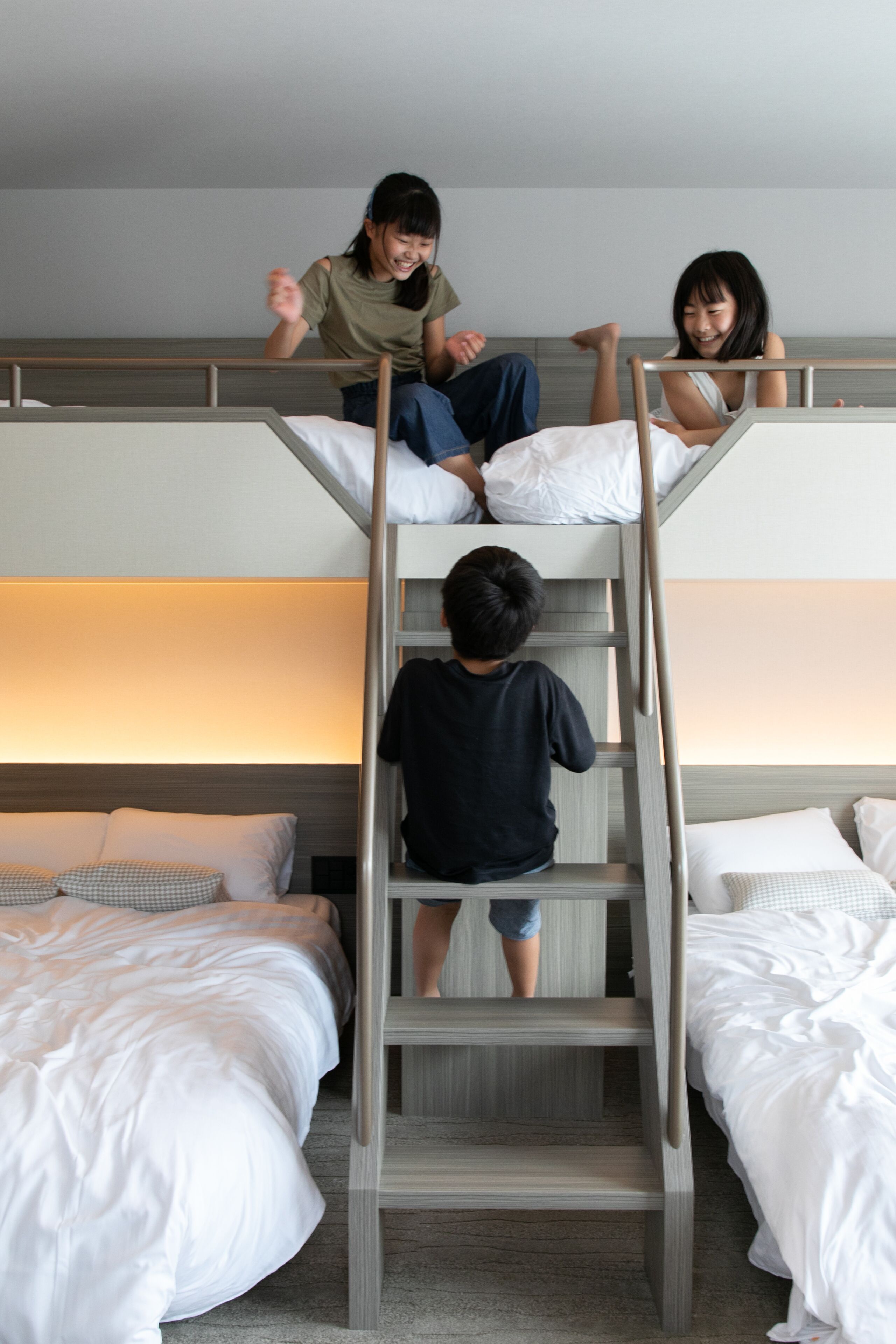 A bunk bed room with a ladder, two beds, and a nightstand.