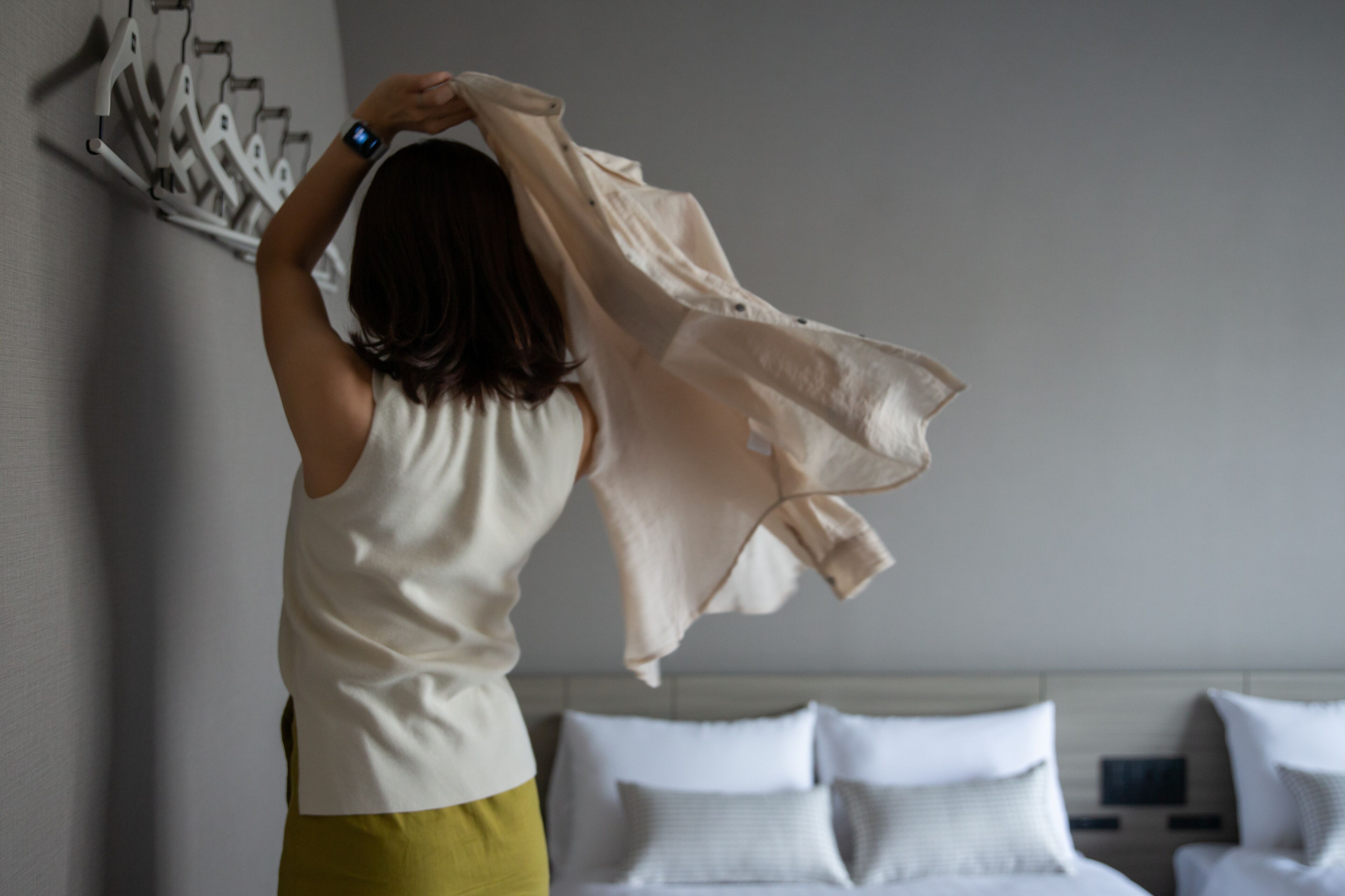 Una persona en una habitación con una cama y un perchero en la pared.