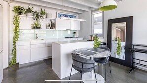 A modern kitchen with white cabinetry, a central island, and a dining area with two chairs.