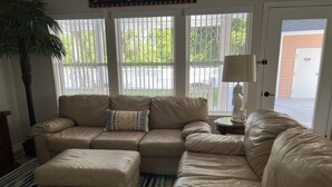 A living room with a beige sectional sofa, a matching ottoman, and a striped rug. - Panama City Beach West Side Gem — Steps to the Beach, Poolside, Ground‑Floor (Panama City Beach)