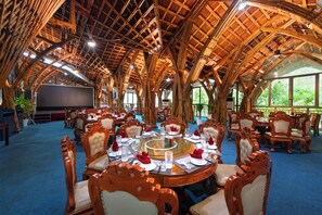 Une grande pièce dotée d’un plafond voûté et d’une table ronde placée au centre, préparée pour le repas.