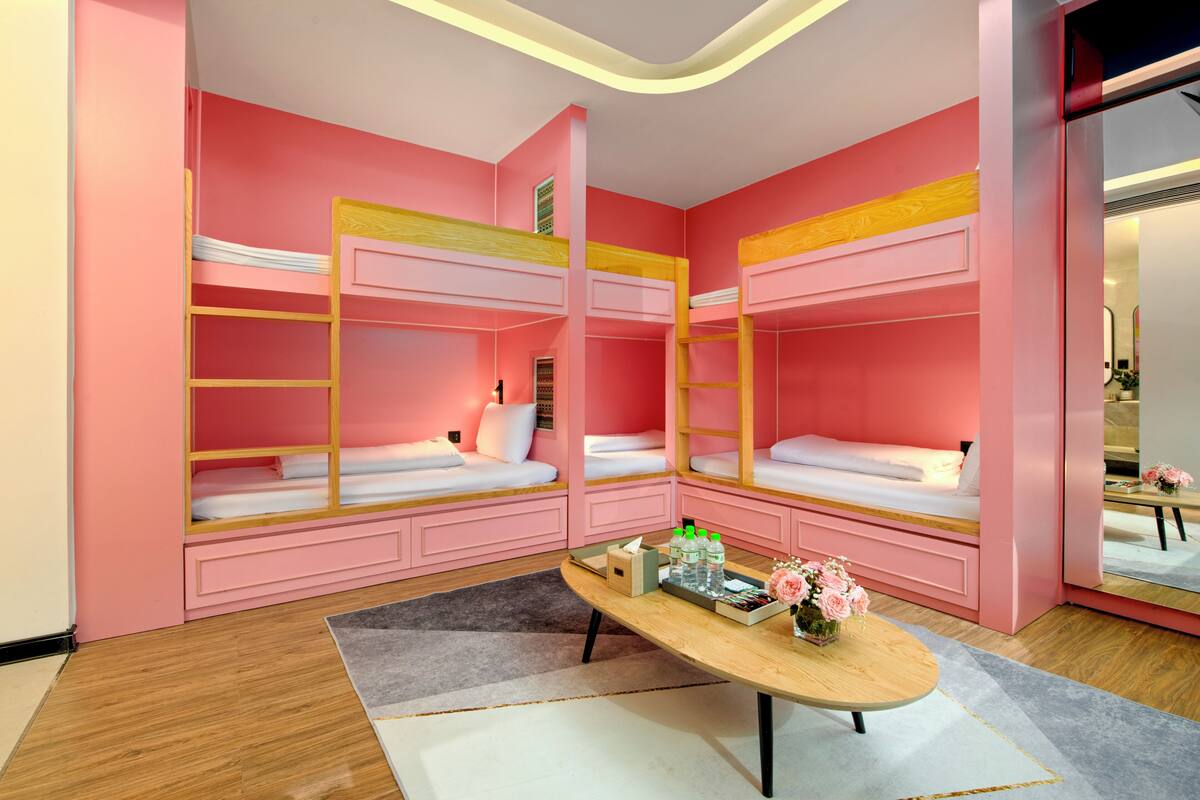 A room with bunk beds, a wooden table, and a mirror.