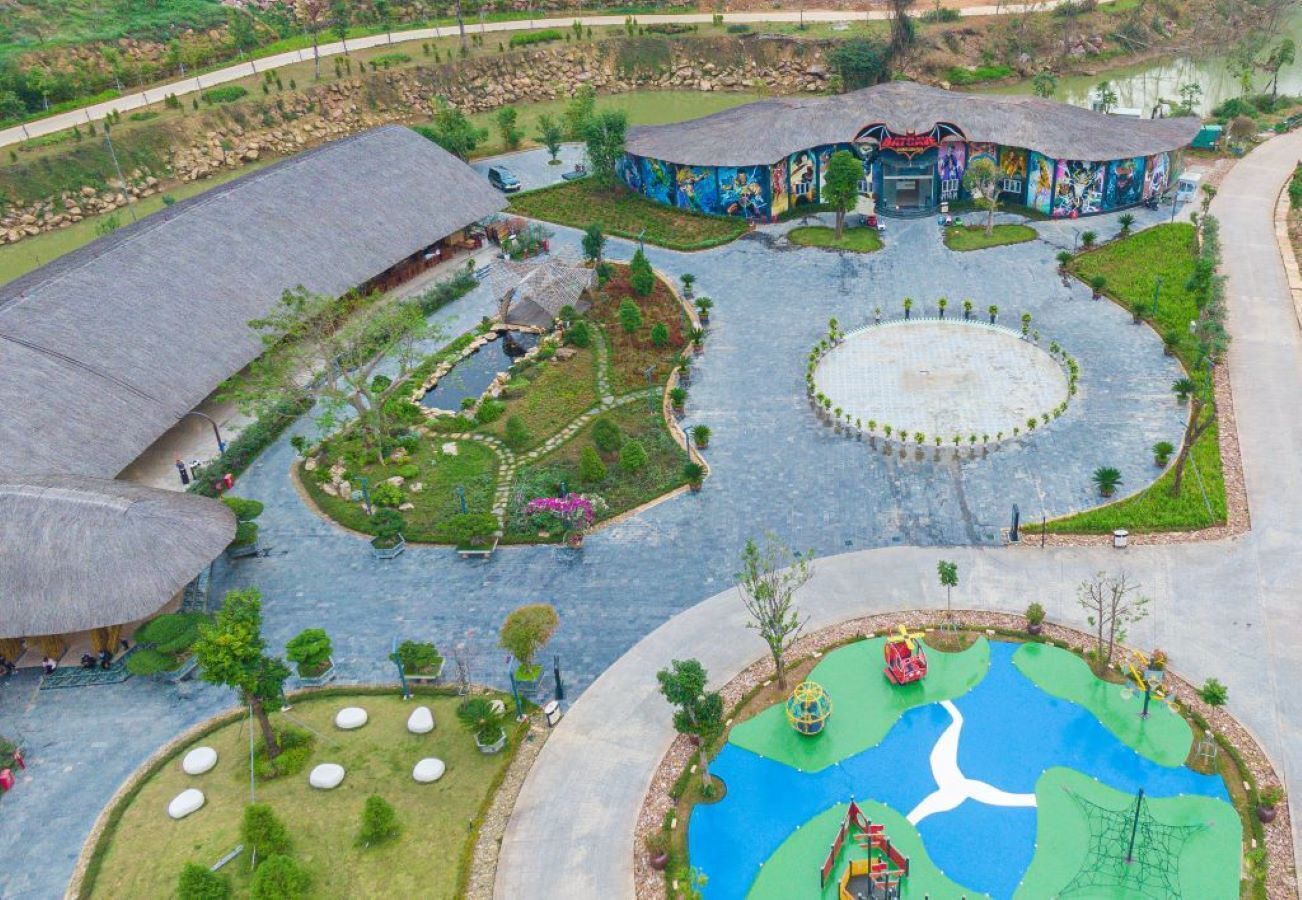 A large, open-air complex with multiple buildings, a central circular plaza, and a playground area.