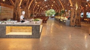 A restaurant with a bamboo ceiling, a central serving counter, and tables arranged for dining. - Moc Chau Island - Mountain Park and Resort (Moc Chau)