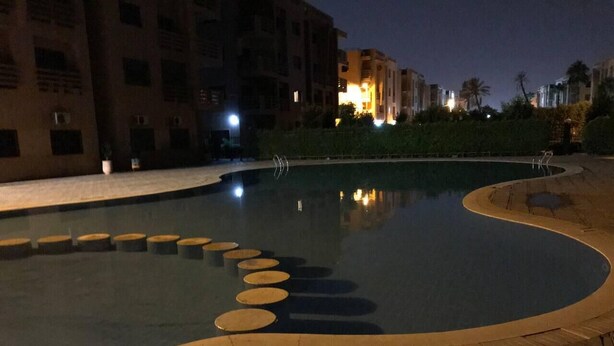 En pool med en buet kant og runde trappesten, omgivet af en fliseterrasse.