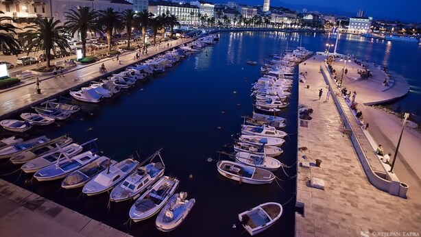 A marina with numerous boats docked, a promenade with palm trees, and buildings in the background. - Apt Sleeps 2 with Sea Proximity (Split)