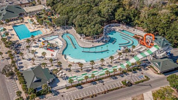 Ein Luftbild zeigt ein Resort mit mehreren Schwimmbecken, einer Wasserrutsche und einem Parkplatz.