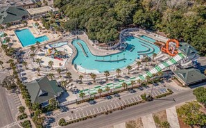 An aerial view of a resort with multiple swimming pools, a water slide, and a parking area. - Cozy Beach Cottage 1758 in Ocean Lakes on Magnolia Lake with Limo Golf Cart (Myrtle Beach)