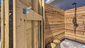 A wooden sauna with a metal door, a showerhead, and a wooden bench.