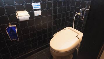 Un baño con inodoro, secamanos y dispensador de toallas de papel.