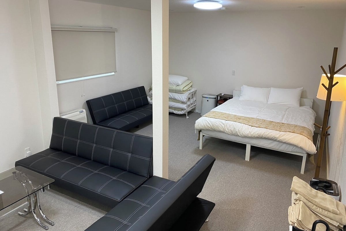 A hotel room with a bed, a sofa, a desk, and a bedside table.