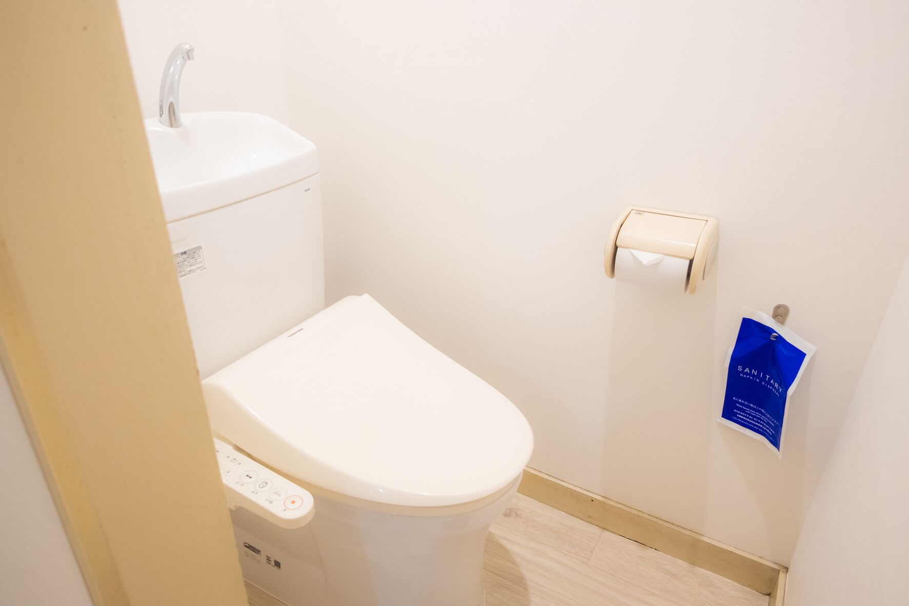 Une petite salle de bain moderne équipée de toilettes, d’un lavabo et d’un distributeur de serviettes en papier.