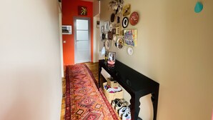 A hallway with a patterned carpet, a bench, and various wall decorations including framed pictures and a clock.