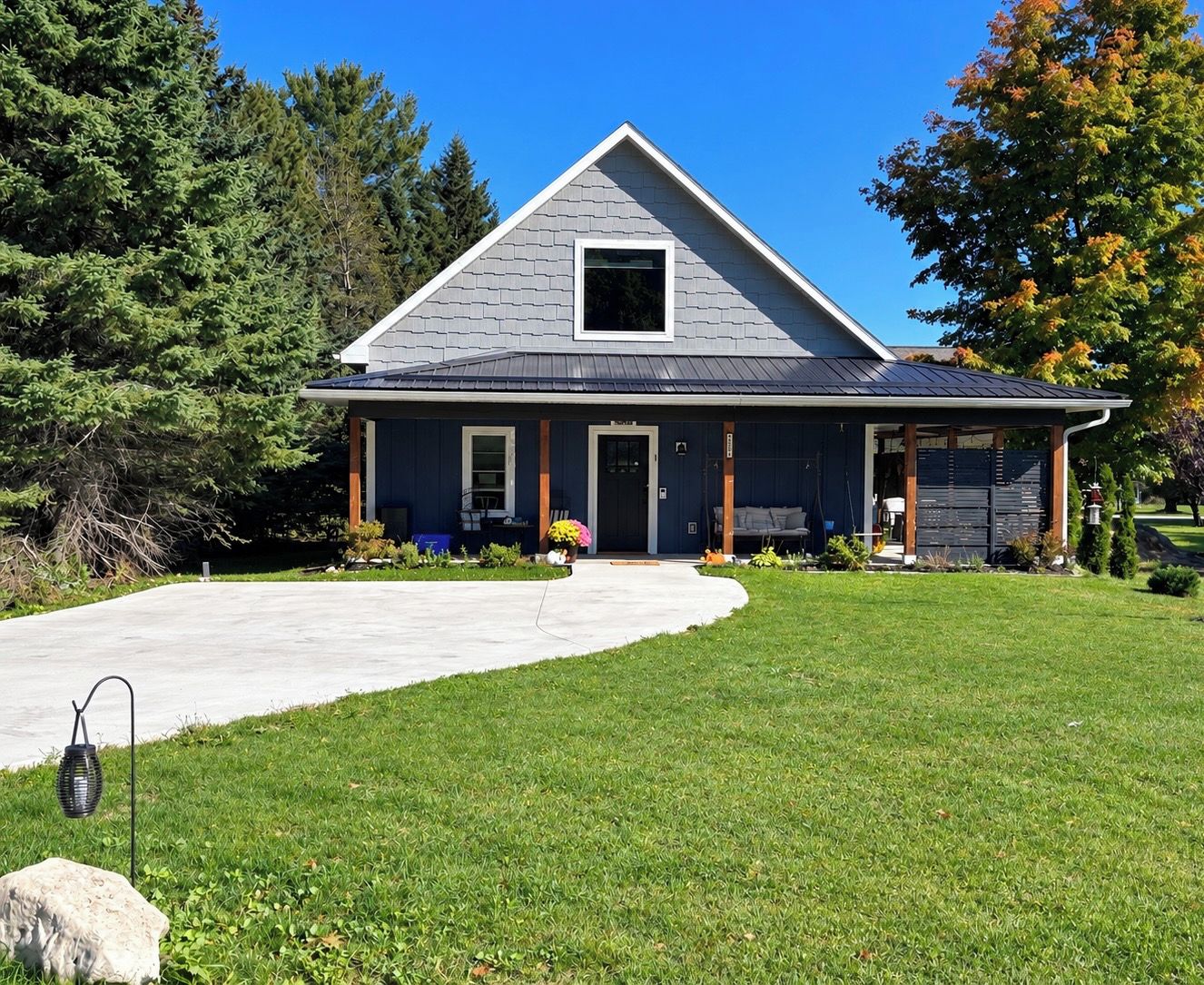 A two-story house with a grey roof, a front porch, and a driveway.