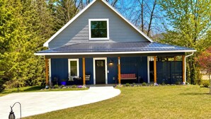 A single-story house with a covered porch, a front door, and a small window. - King Bed~Cedar soaking Hot Tub~5min walk to Beach~No Cleaning Fee (Two Rivers)