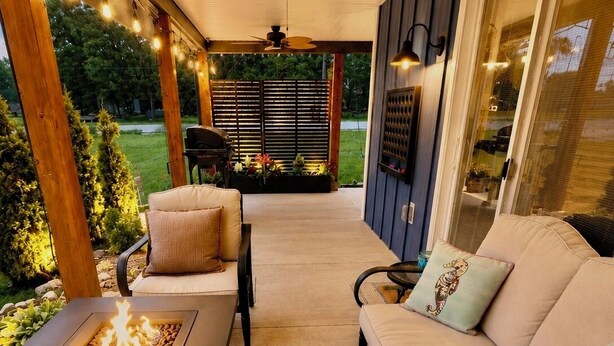 A covered patio area with a fire feature, seating, ceiling fans, and a view of the outdoors. - King Bed~Cedar soaking Hot Tub~5min walk to Beach~No Cleaning Fee (Two Rivers)