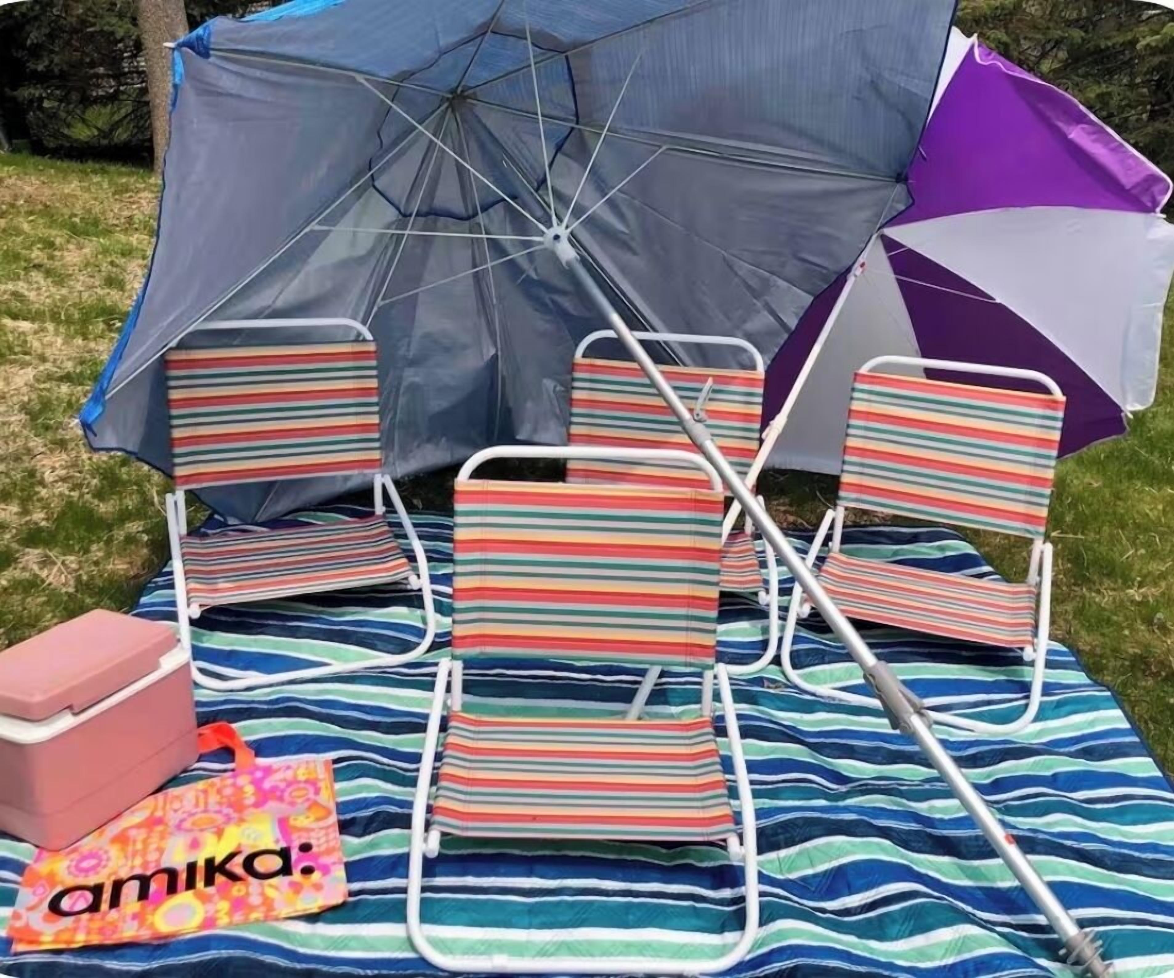 En picknickplats med randiga strandstolar, ett picknickbord och ett blått parasoll.