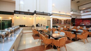 A spacious dining area with multiple tables and chairs, a buffet line with food containers, and a patterned wall. - apvc-resort (Lukang)