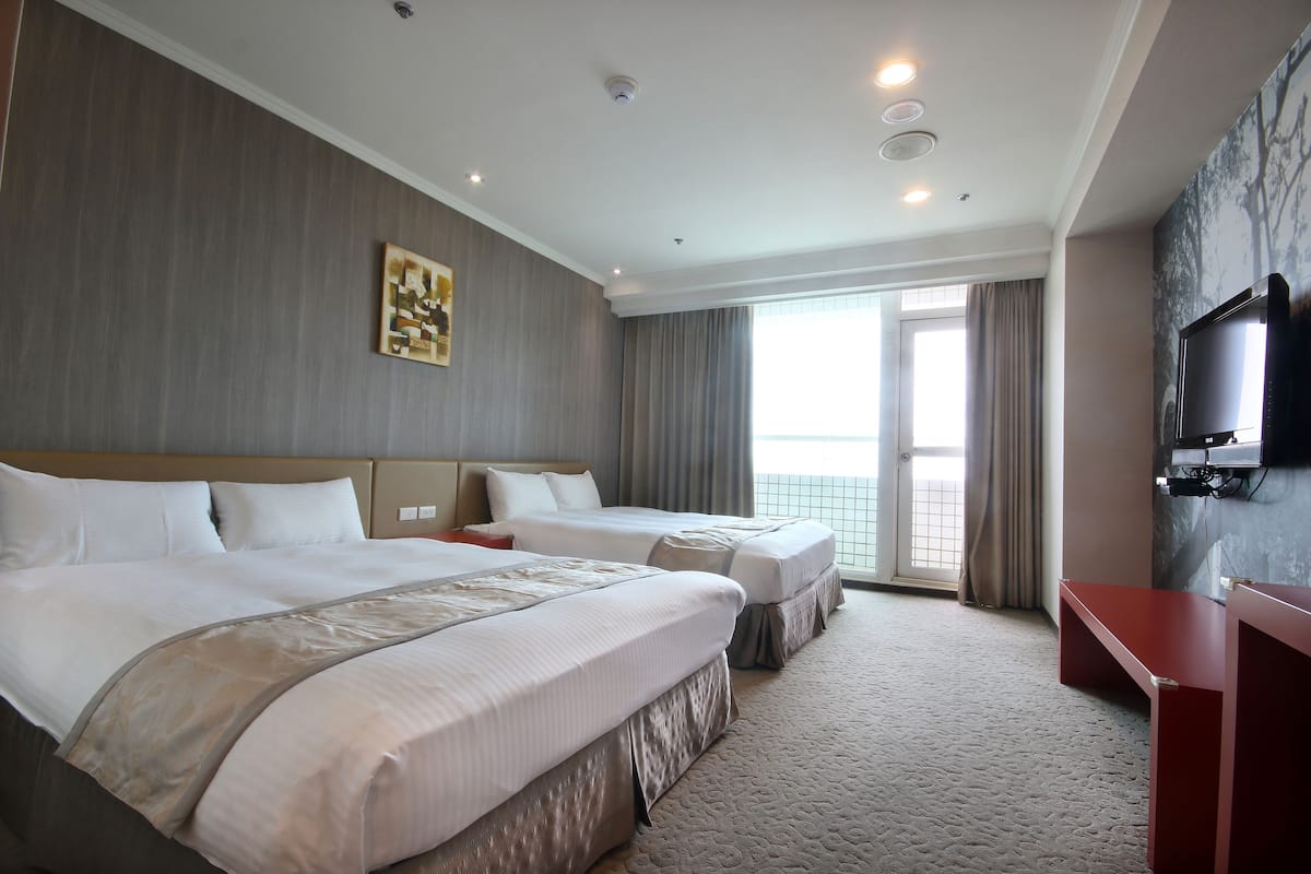 Quarto de hotel com duas camas, televisão e varanda.