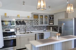 Une cuisine moderne dotée d’appareils électroménagers en acier inoxydable, de meubles blancs et d’un îlot central.