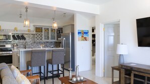A modern kitchen with a central island, bar stools, and pendant lighting. - Breathtaking views 5min from the beach! (Old Road Village)