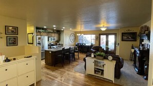 A spacious living area with a kitchen, dining area, and a cozy seating space with a fireplace. - Beautiful Getaway Near Park City with Private Hot Tub (Kamas)