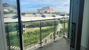 Een balkon met uitzicht op een parkeerplaats en een gebouw aan de overkant van de straat.