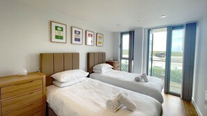 Een hotelkamer met twee bedden, een houten dressoir en een groot raam met uitzicht.