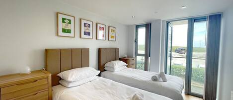 A hotel room with two beds, a wooden dresser, and a large window with a view of the outside.