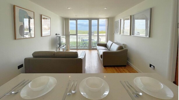 Een ruime woonkamer met een eettafel voor vier personen, een bank en een balkon met uitzicht.