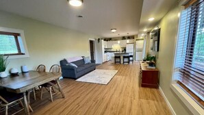 Amplia sala de estar con una mesa de comedor, sofá y cocina al fondo.