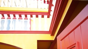 A red door with an anchor handle, a yellow wall, and a blue chair outside. - Trojan Beach House (Ensenada)