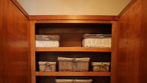 A wooden storage cabinet with multiple shelves containing baskets and bins. - Trojan Beach House (Ensenada)