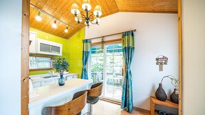 Een keuken met een houten plafond, een raam met gordijnen en een welkomstbord.