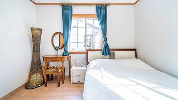 Un dormitorio con cama, mesita de noche, espejo, silla y un jarrón grande.