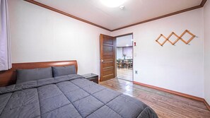 Un dormitorio con cama, cabecera de madera y puerta que da a un comedor.