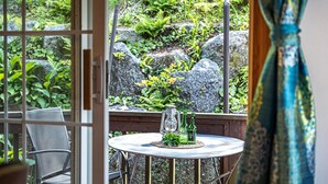 Een terras met een ronde tafel, metalen stoelen en een lantaarn.
