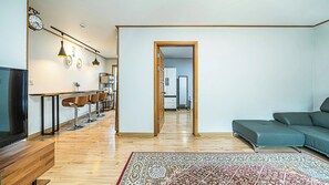 Een moderne woonkamer met een bank, een televisie, een houten vloer en een kamerkleed met een patroon.