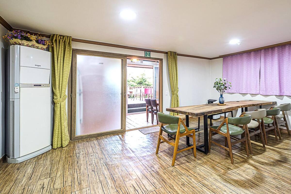 Un coin repas avec une table et des chaises en bois, un réfrigérateur et une fenêtre ornée de rideaux violets.