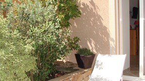 A patio area with a stone planter, a white chair, and a potted plant. - 30 m2 in a Villa - Grand Ajaccio (peri)
