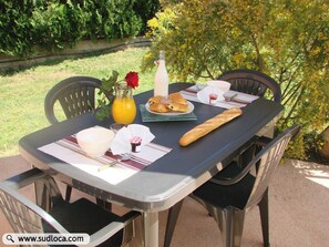 A table set outdoors with a bottle of milk, a glass of orange juice, a baguette, a plate of pastries, and a rose. - 30 m2 in a Villa - Grand Ajaccio (peri)